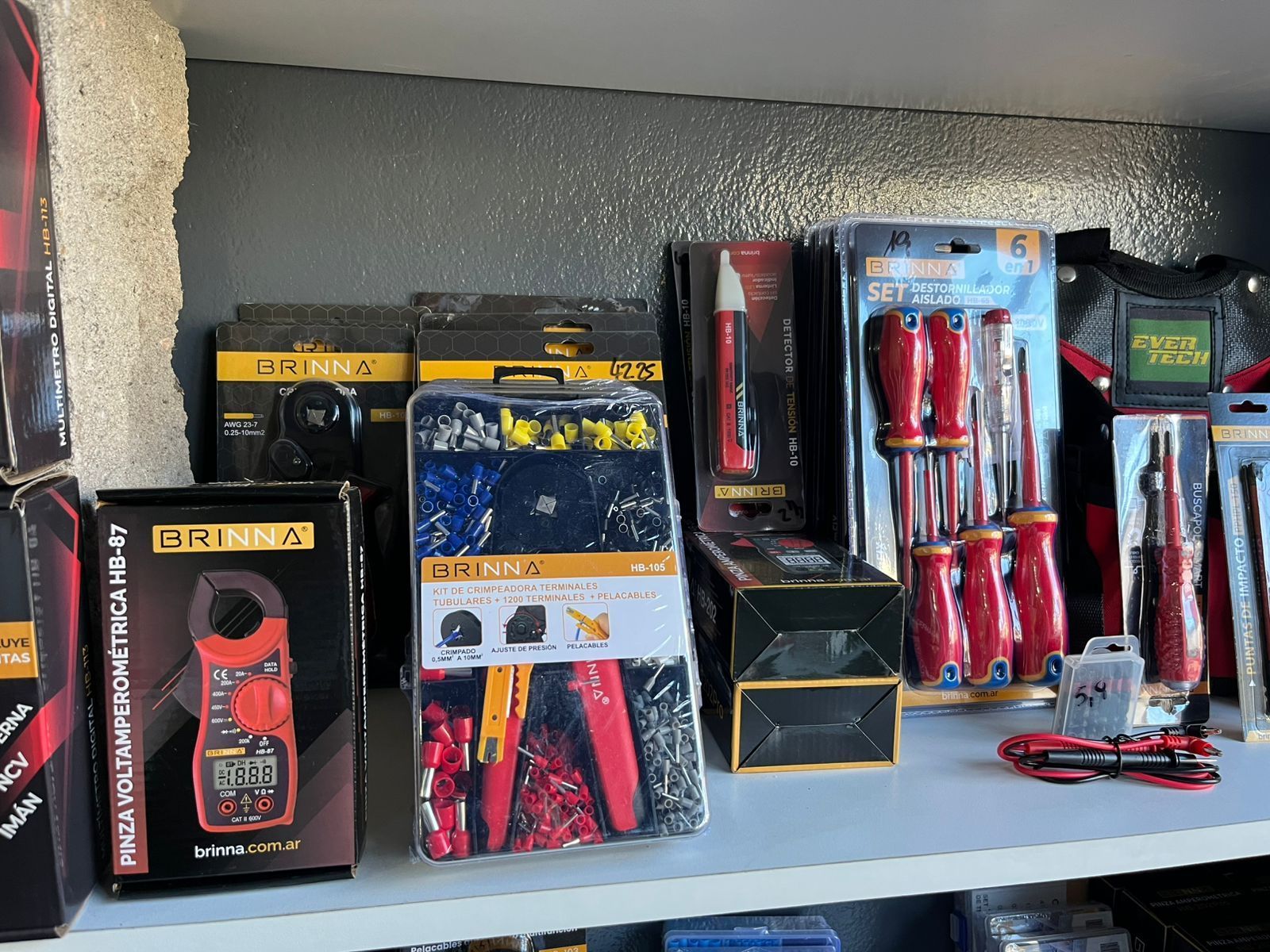 Variedad de herramientas manuales en cajas, con embalaje rojo y negro, expuestas en un estante.