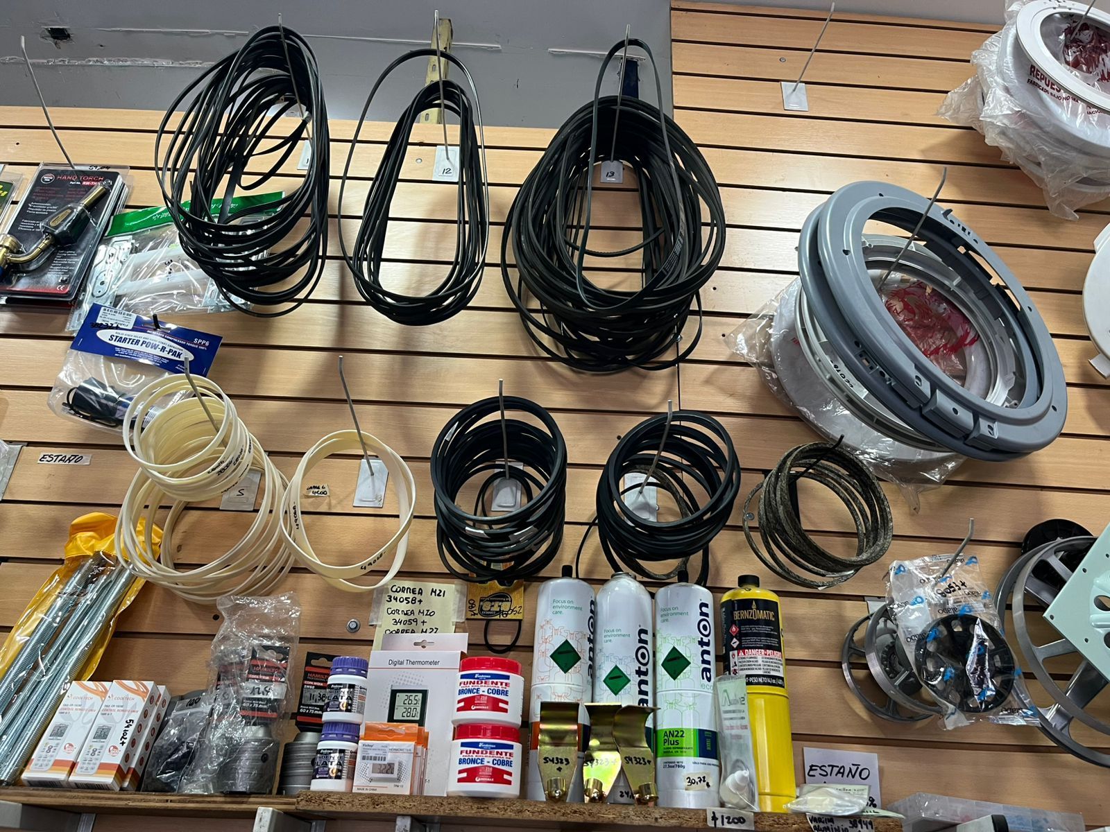 Cables eléctricos, bobinas, conectores y piezas de hardware de diversos tipos dispuestos sobre una mesa de exposición.