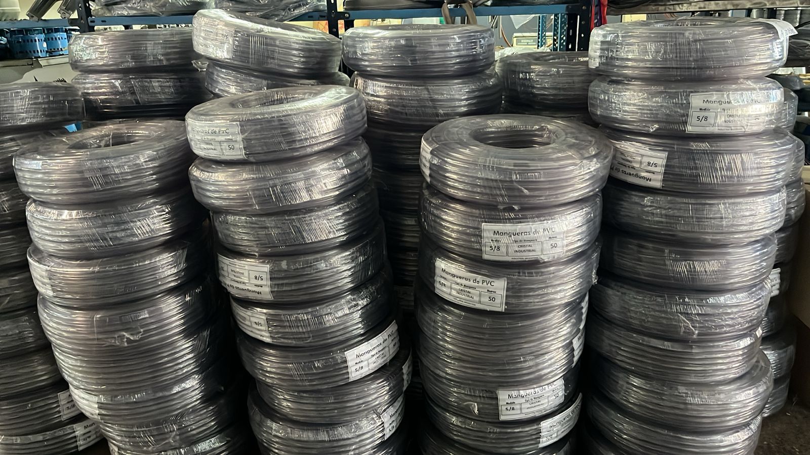 Montones de bobinas de alambre metálico enrolladas, apiladas en filas en un almacén industrial.