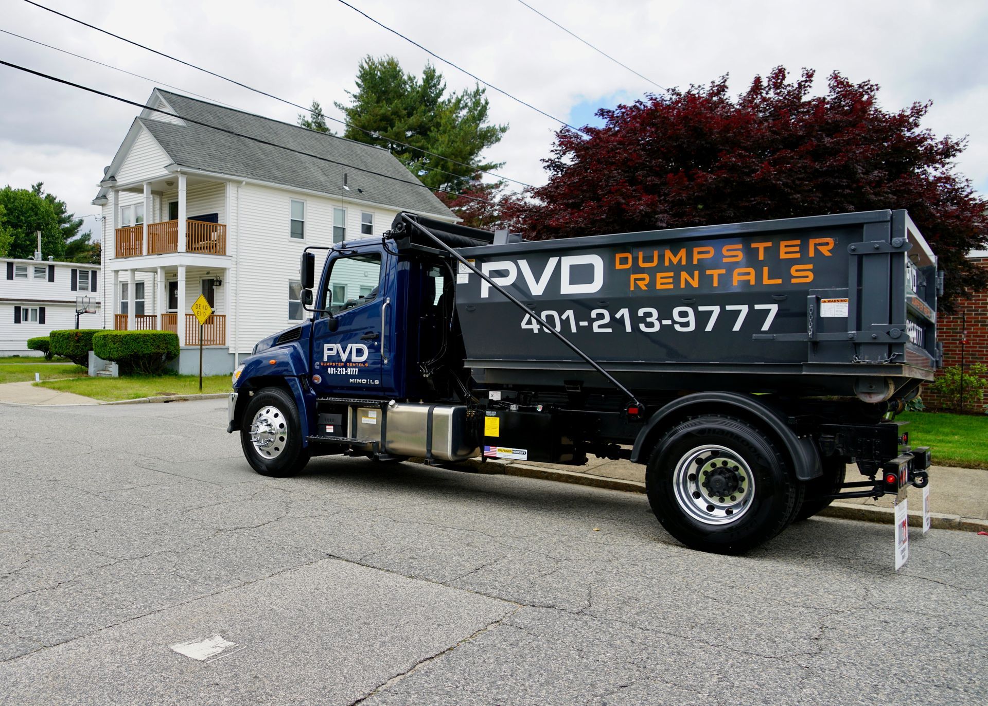 A dumpster filled with wood and rocks is sitting in front of a building under construction.