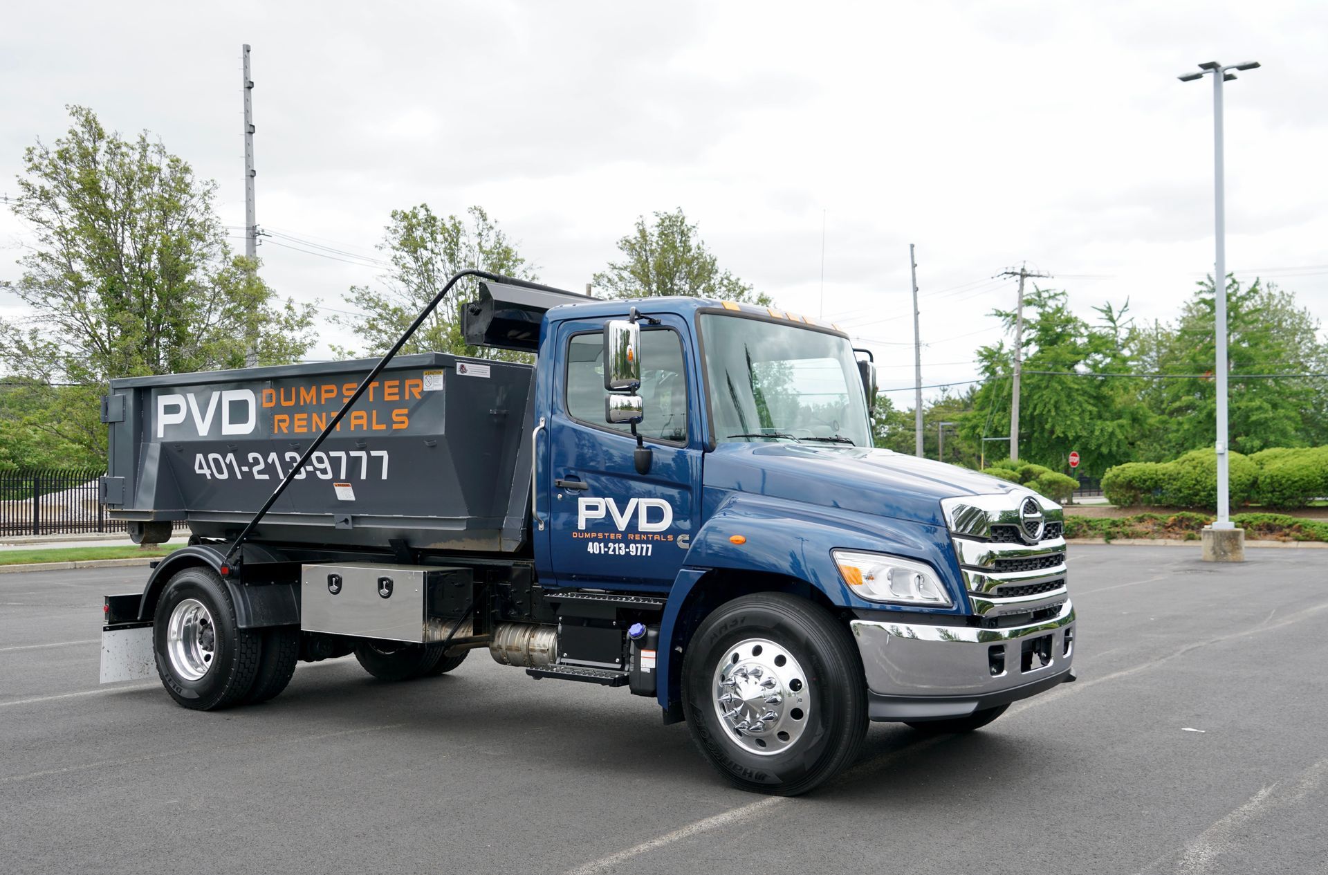 A black dumpster is sitting on the side of a road.