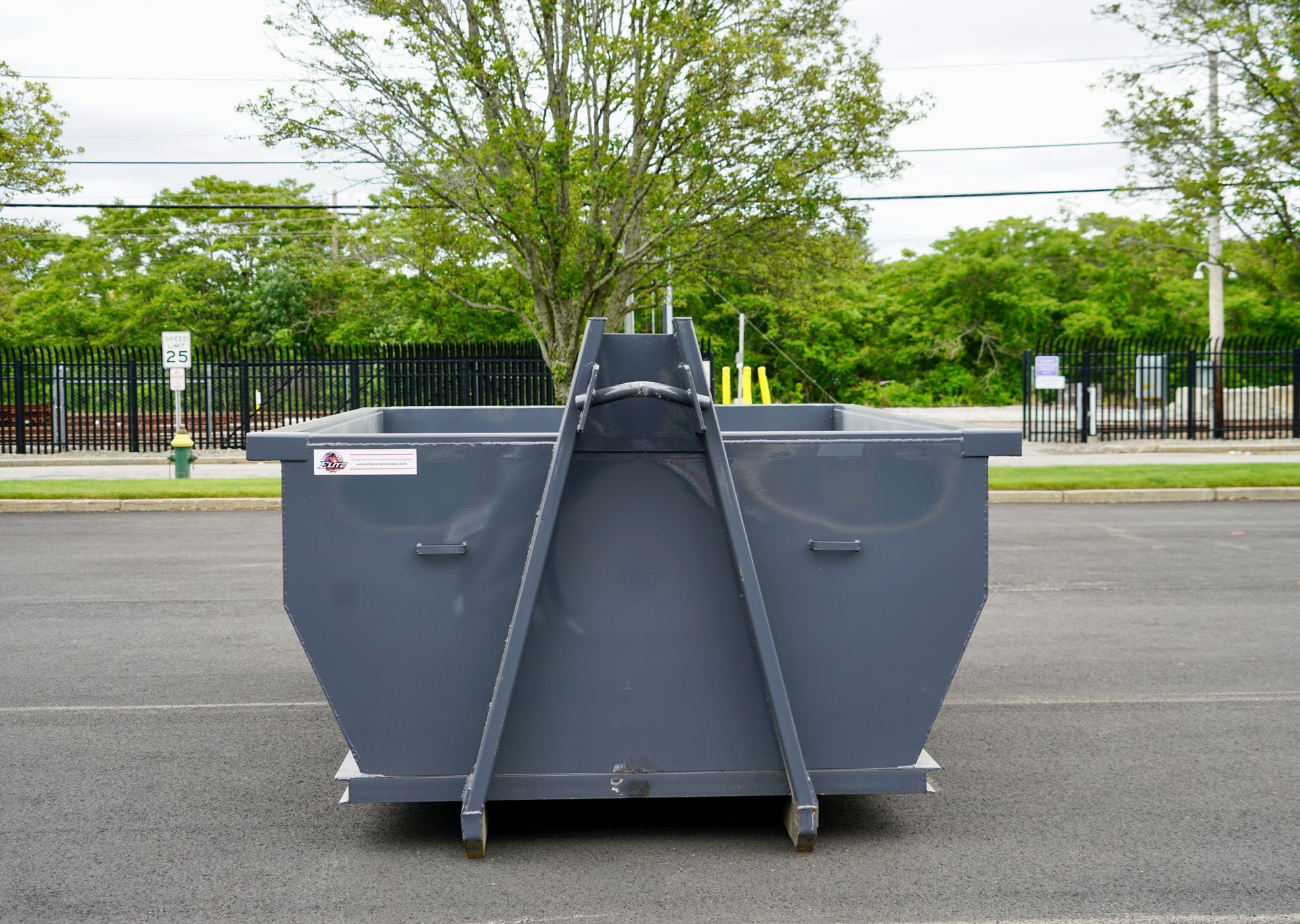 A green dumpster is parked in front of a building.