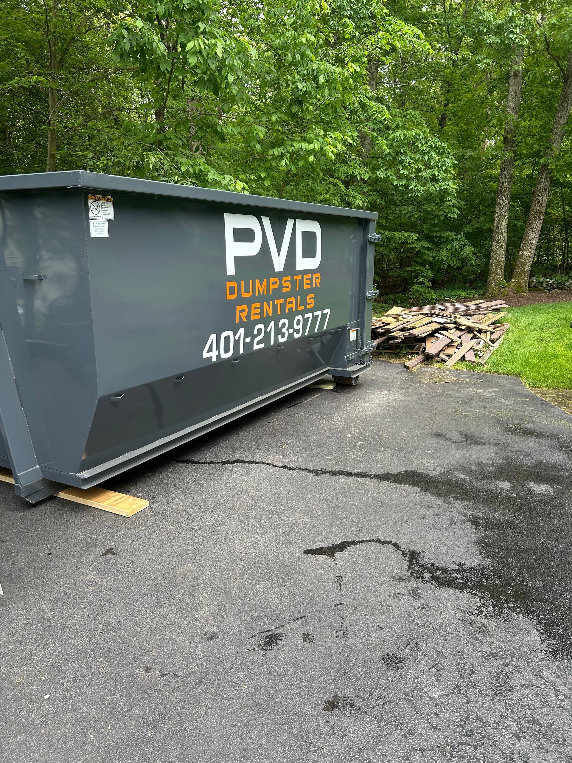 A dumpster filled with wood and rocks is sitting in front of a building under construction.