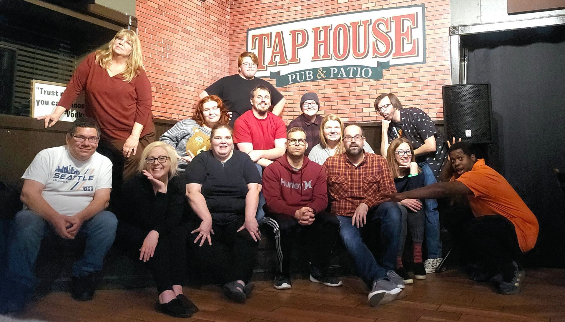 A group of people are posing for a picture in front of a sign that says tap house