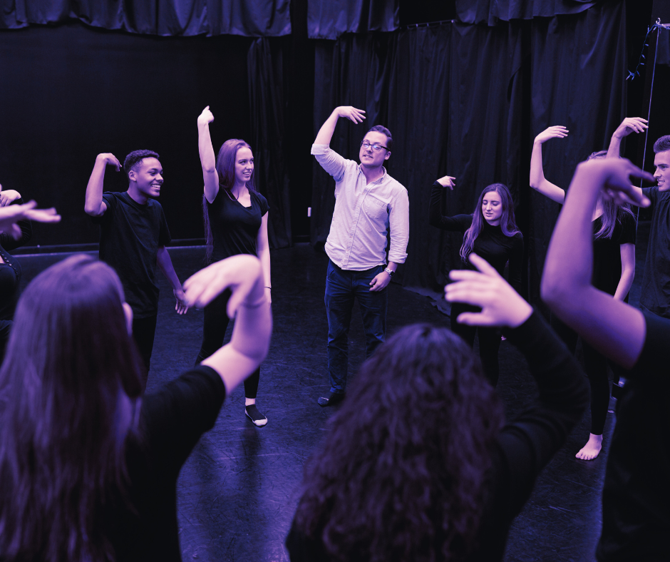 A group of people are dancing in a dark room