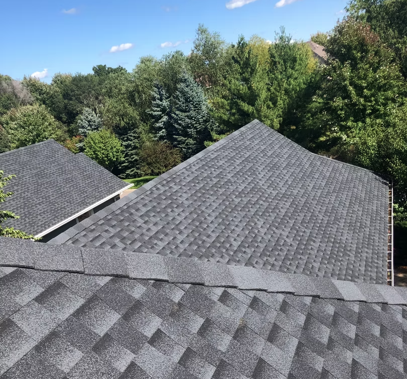 Gray tile roof on a light green building against a cloudy blue sky.