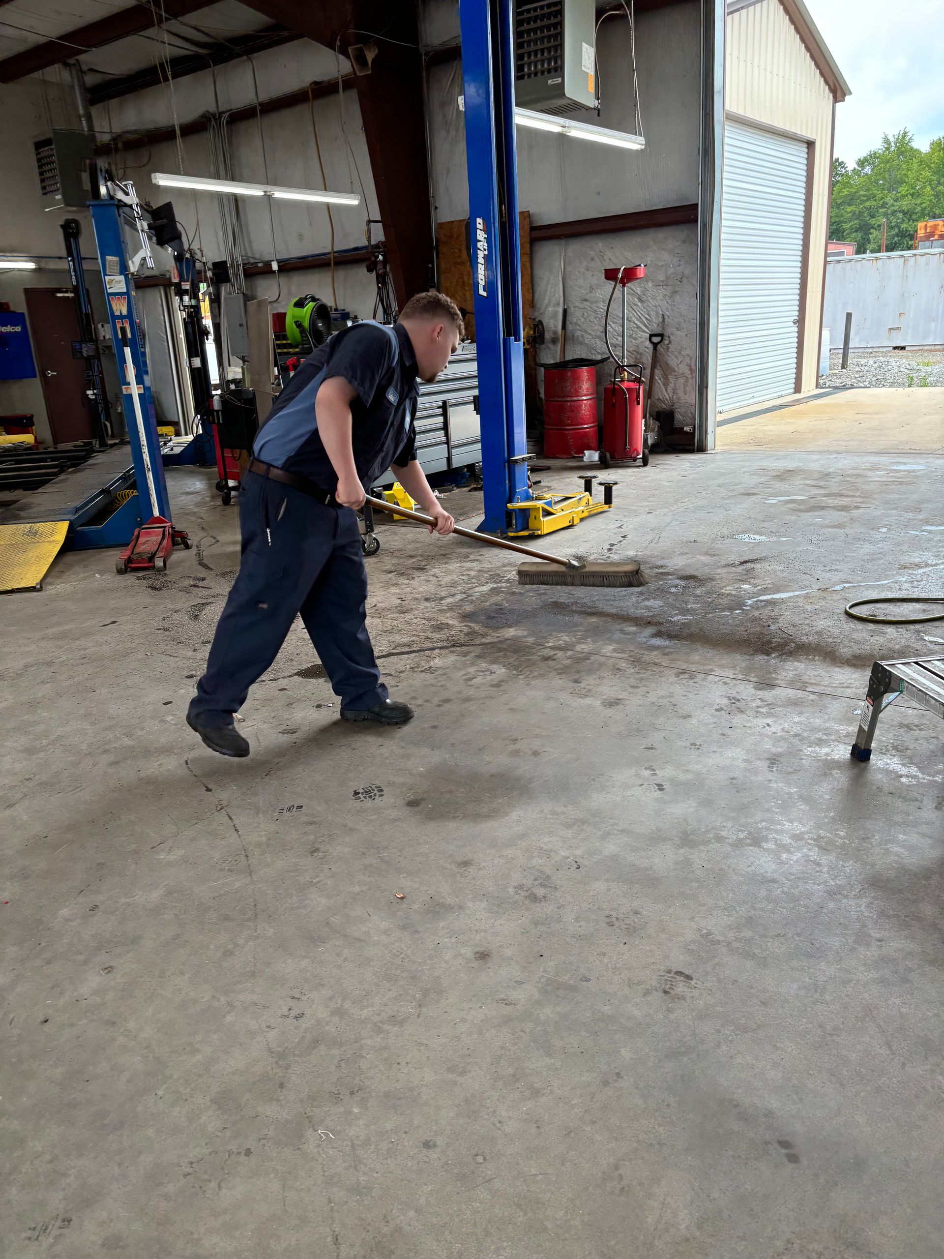 Mechanic sweeping a concrete shop floor with a broom | Stephen's Automotive