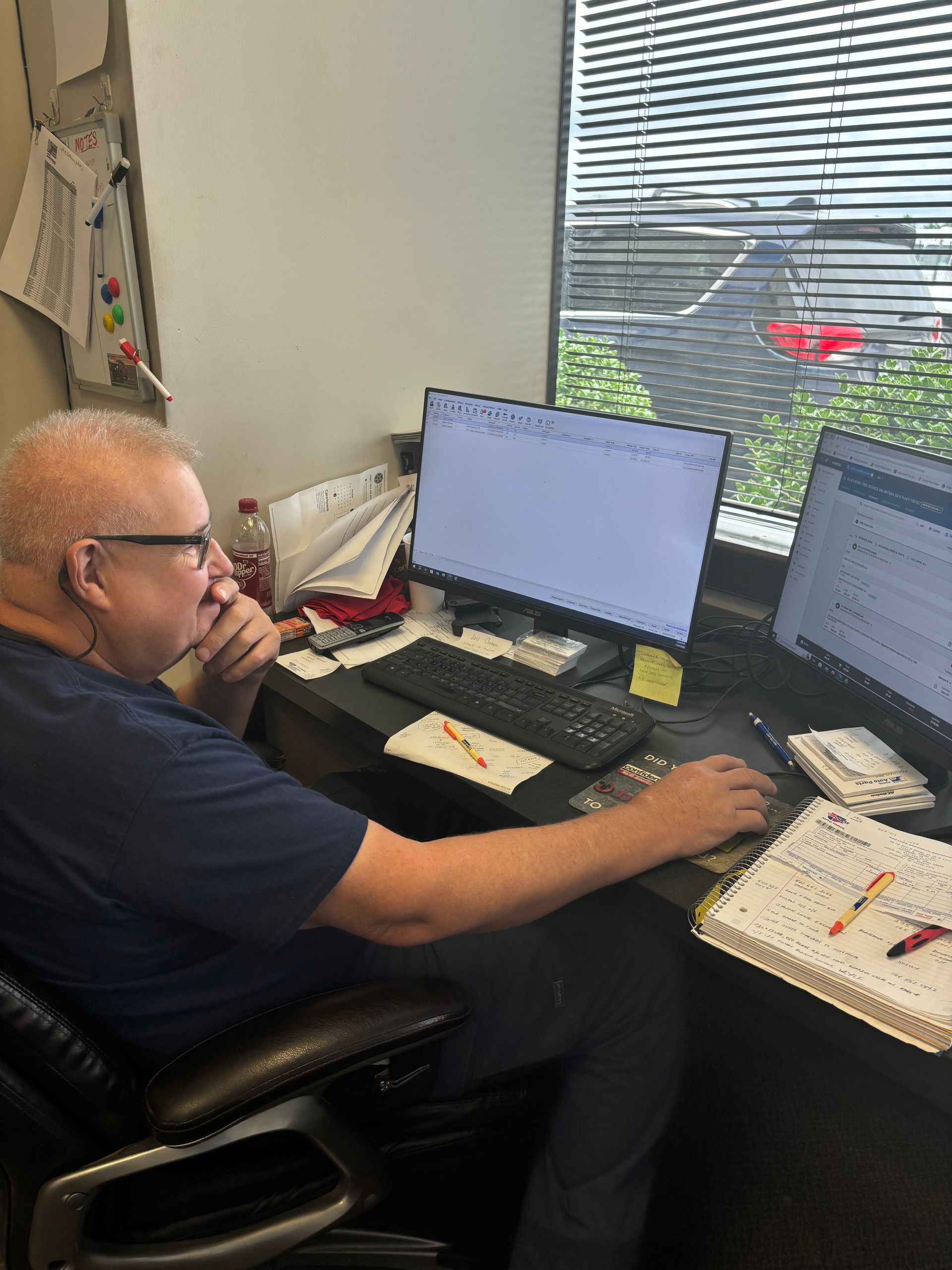 Man at a desk, looking at computer screens, near a windowy | Stephen's Automotive