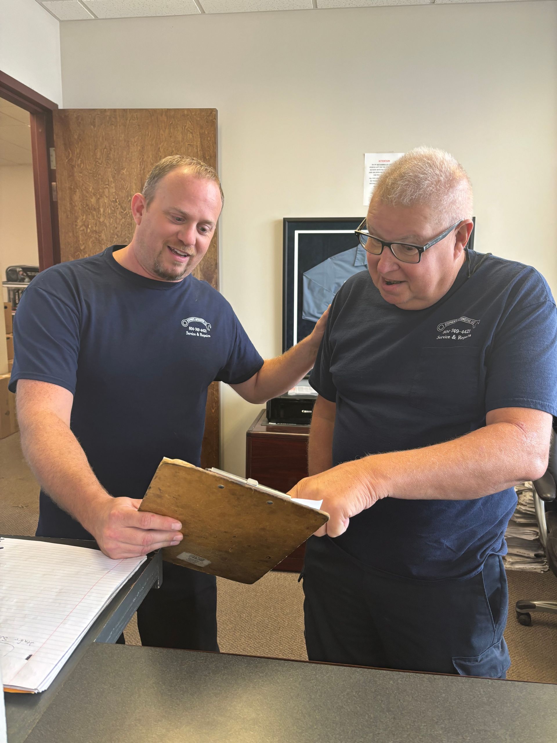Mechanics looking at a clipboard | Stephen's Automotive