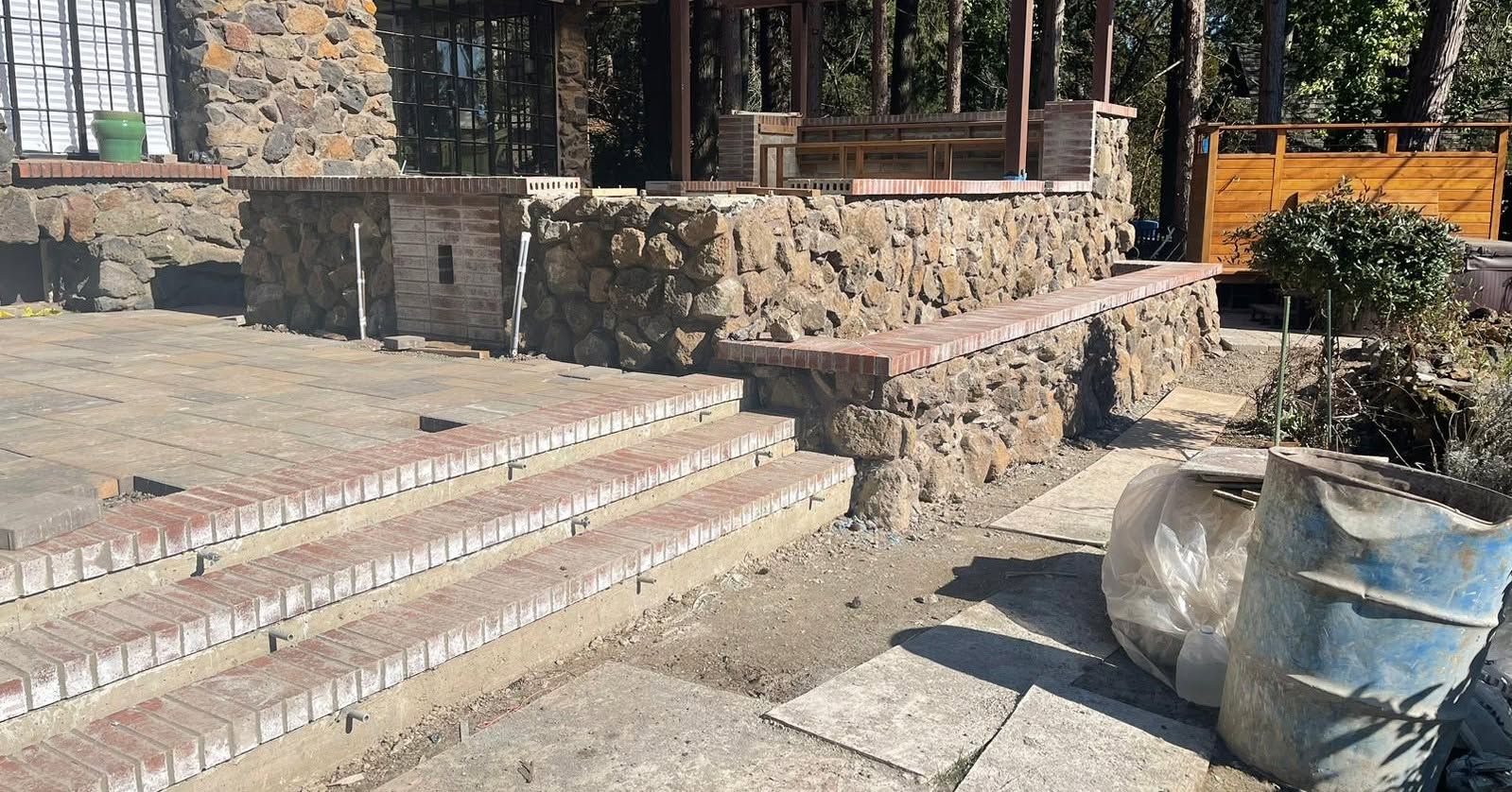 Brick steps lead up to a stone patio with a gazebo and large planter.