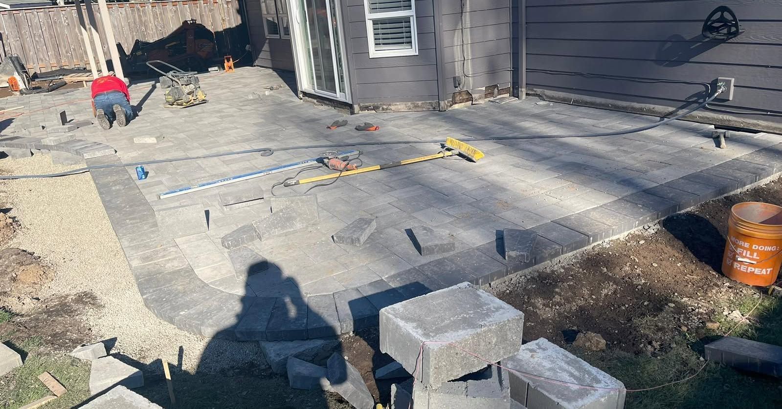 Construction of a patio with paving stones, concrete, and building materials.