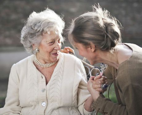 A young woman is holding the hand of an older woman.