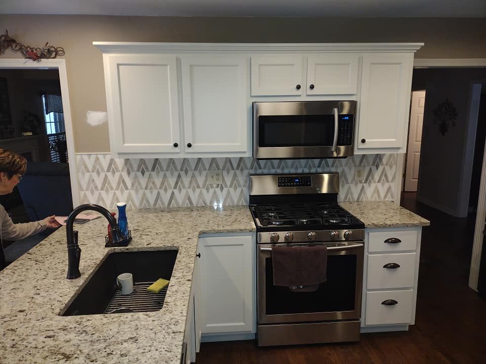 Kitchen with white cabinets, stainless steel appliances, and patterned backsplash.