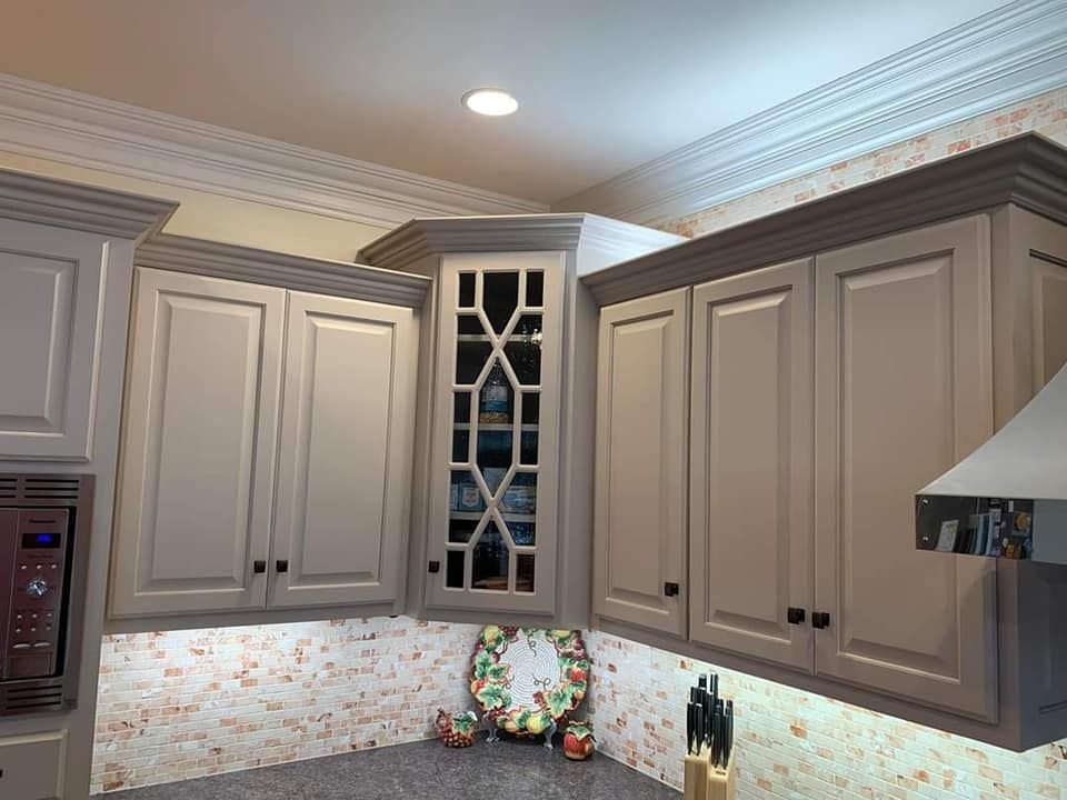 Gray kitchen cabinets with a glass-front display cabinet, above a backsplash and countertop.