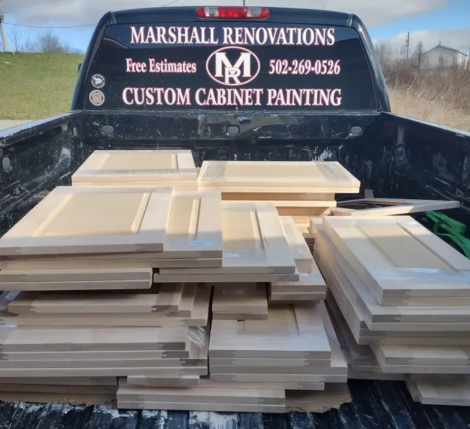Cabinet doors stacked in a pickup truck bed, for custom painting by Marshall Renovations.
