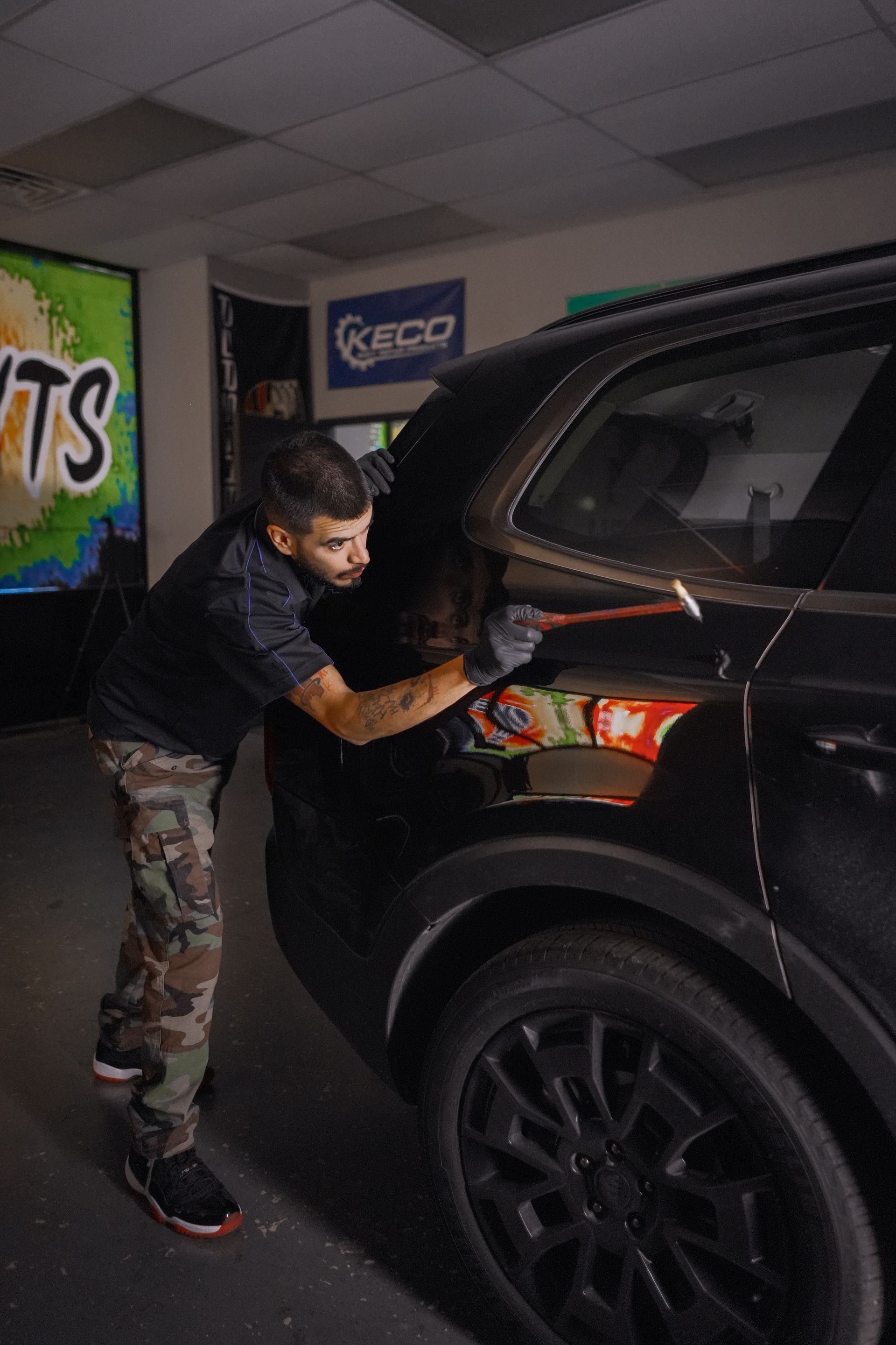 a man working on a car with a hammer.