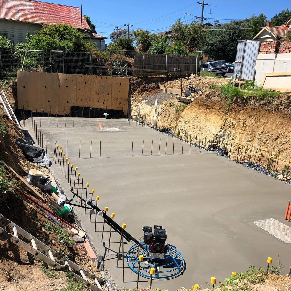 Construction site with freshly poured concrete slab; power trowel in use. 