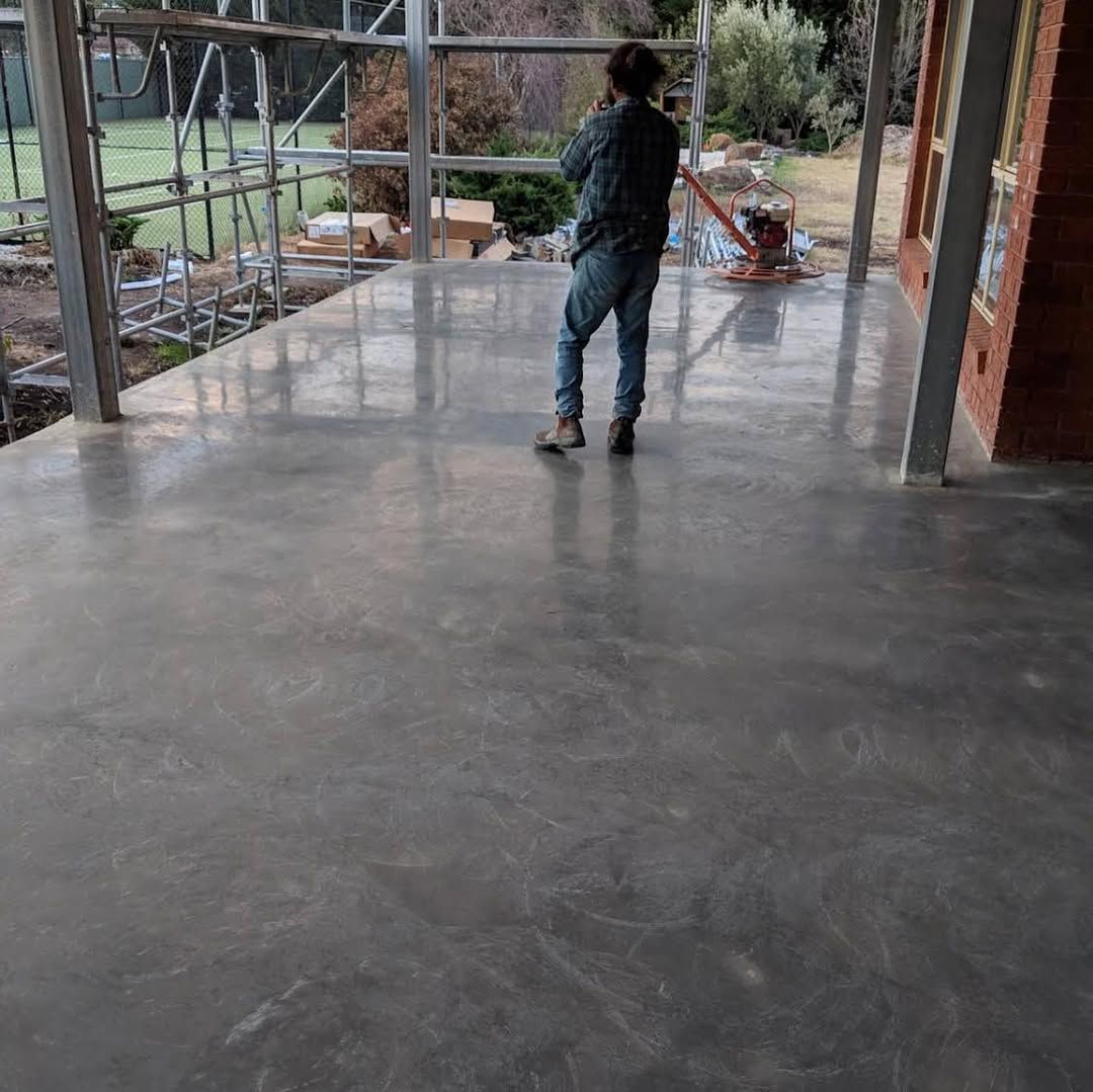 Person stands on a polished concrete porch under construction.