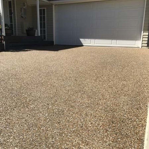 Gravel driveway in front of a white garage door, leading to a house entrance.