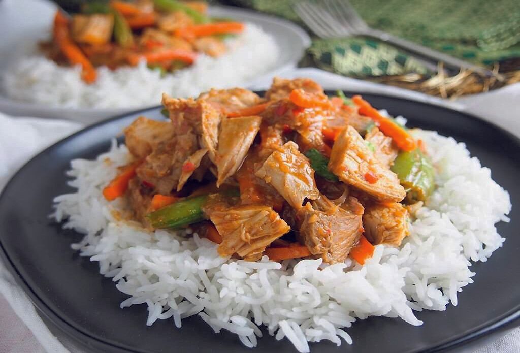 Un gros plan d'une assiette de nourriture avec du riz et de la viande sur une table.