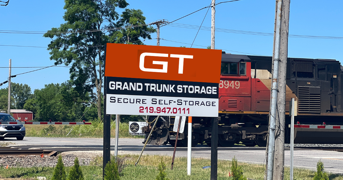 Sign for Grand Trunk Storage with train in background. Orange and white sign.