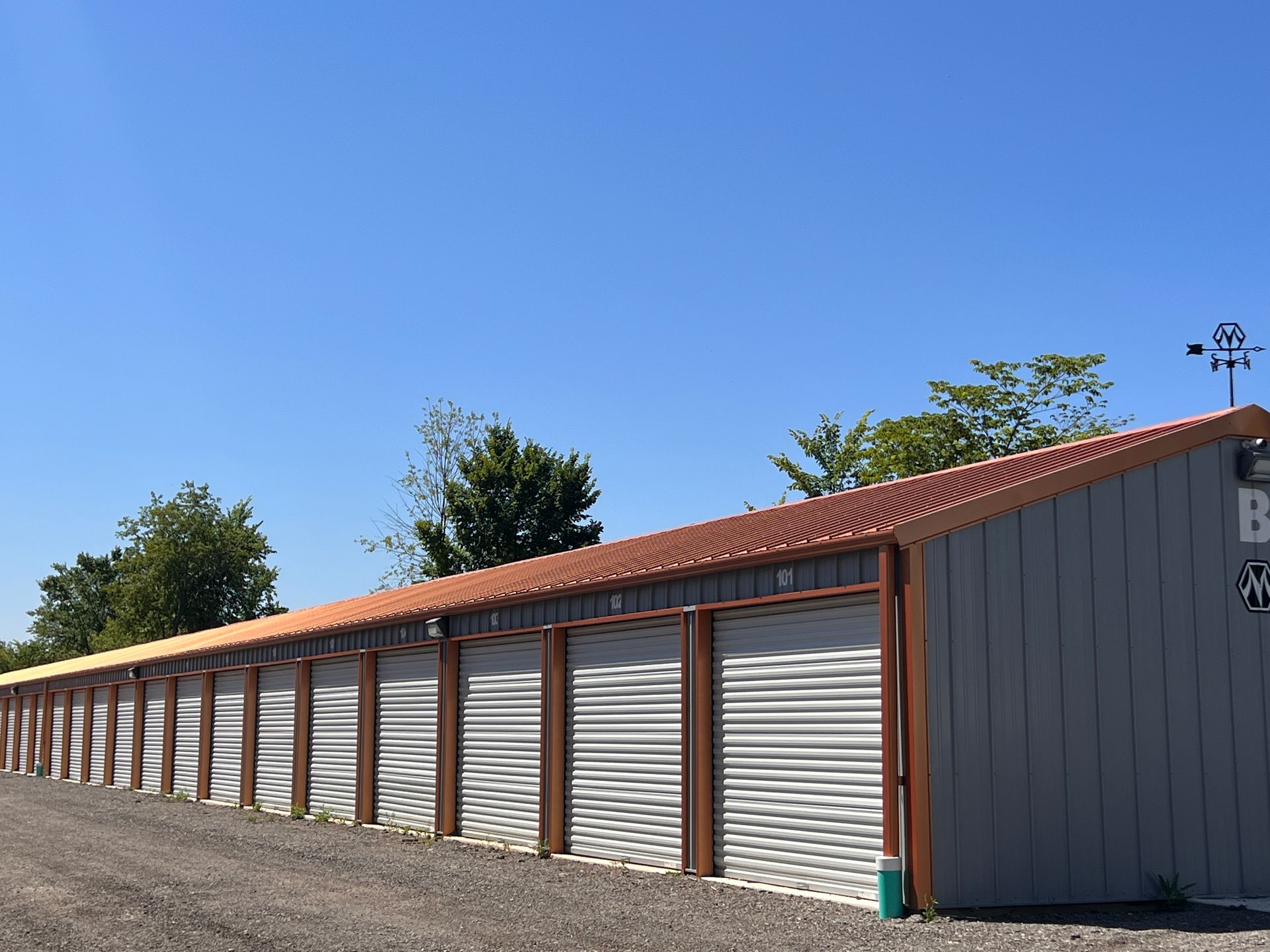 Storage units with corrugated metal doors, gray siding, brown trim, and a copper-colored roof.