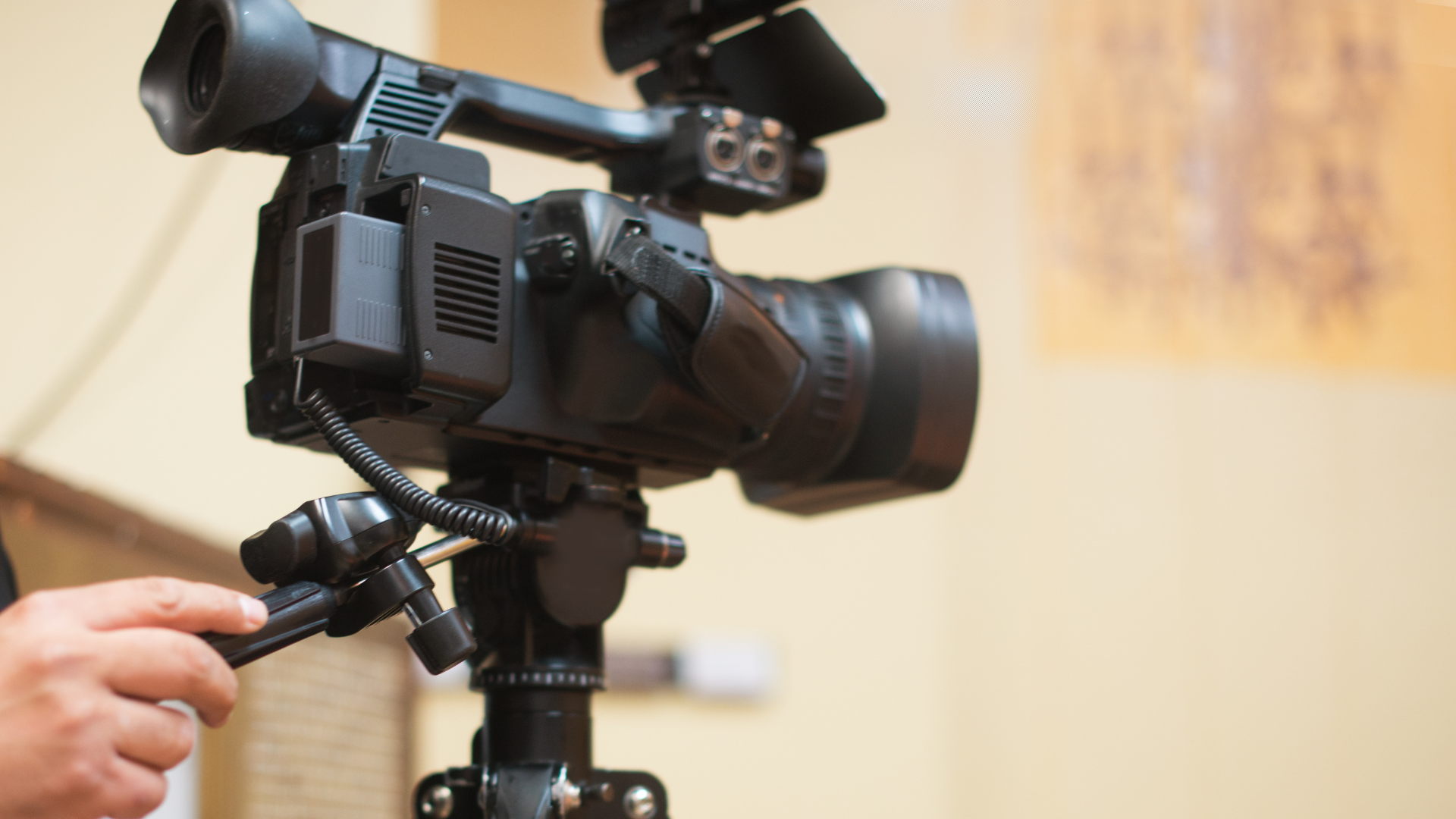 A person is holding a camera on a tripod.