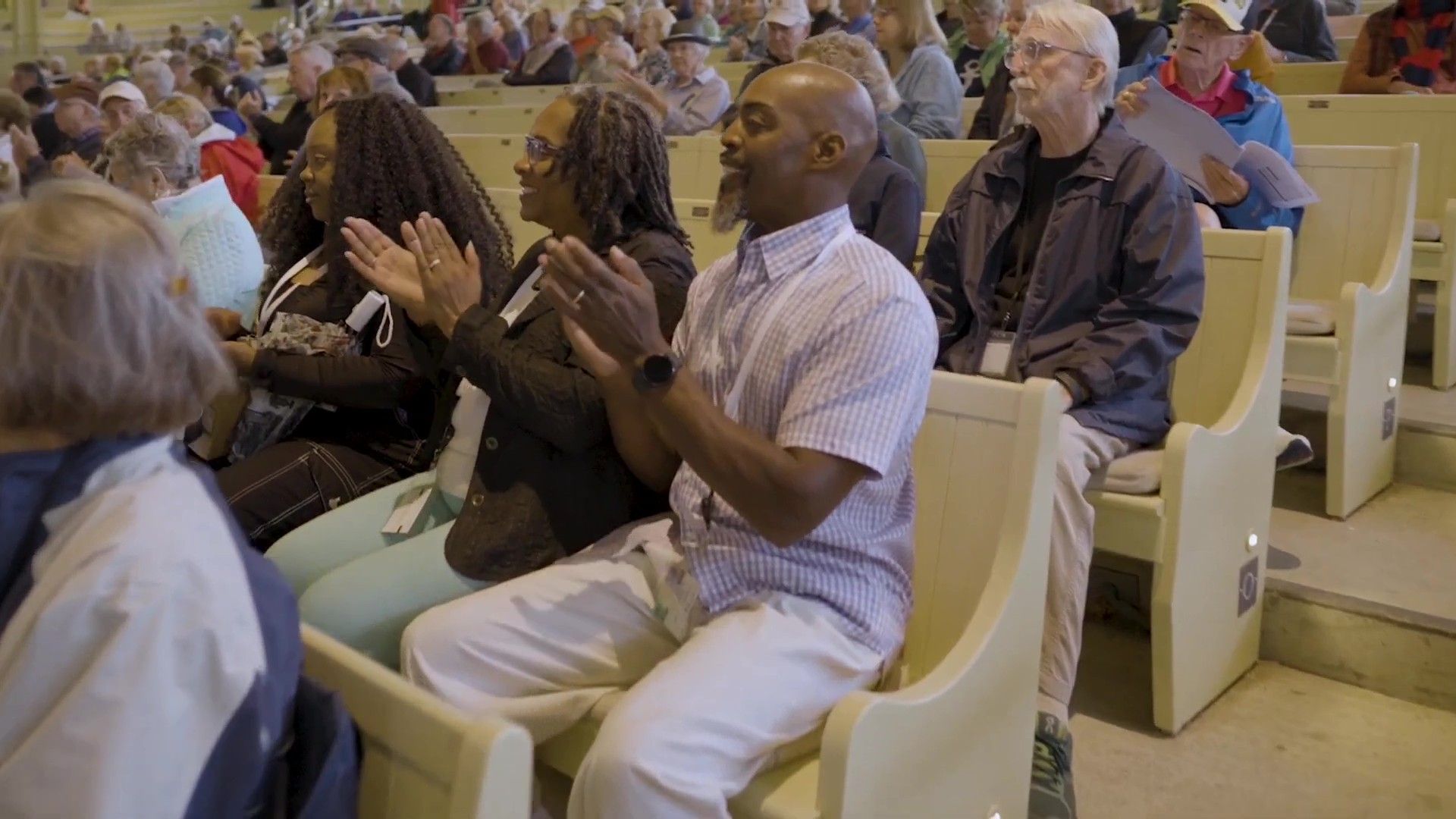 A group of people are sitting in a church applauding.