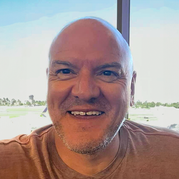 A bald man with a beard is smiling for the camera.