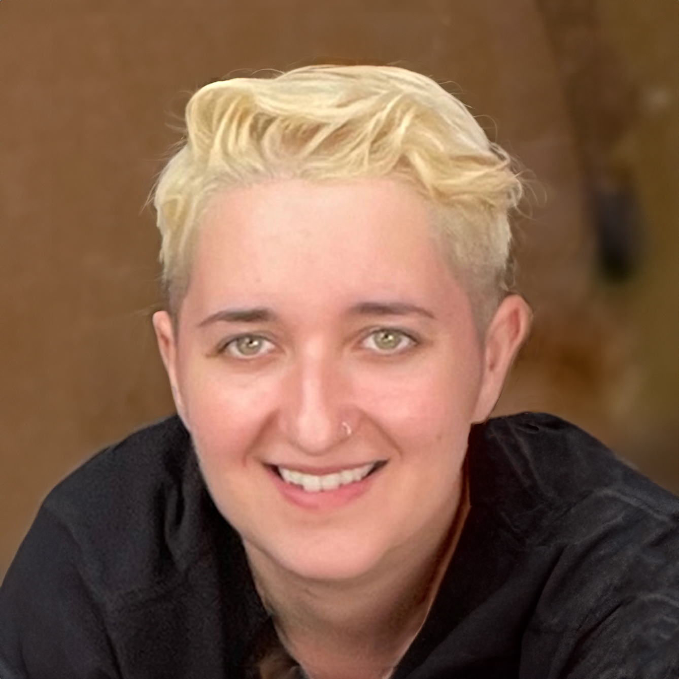 A woman with blonde hair and green eyes is smiling for the camera.
