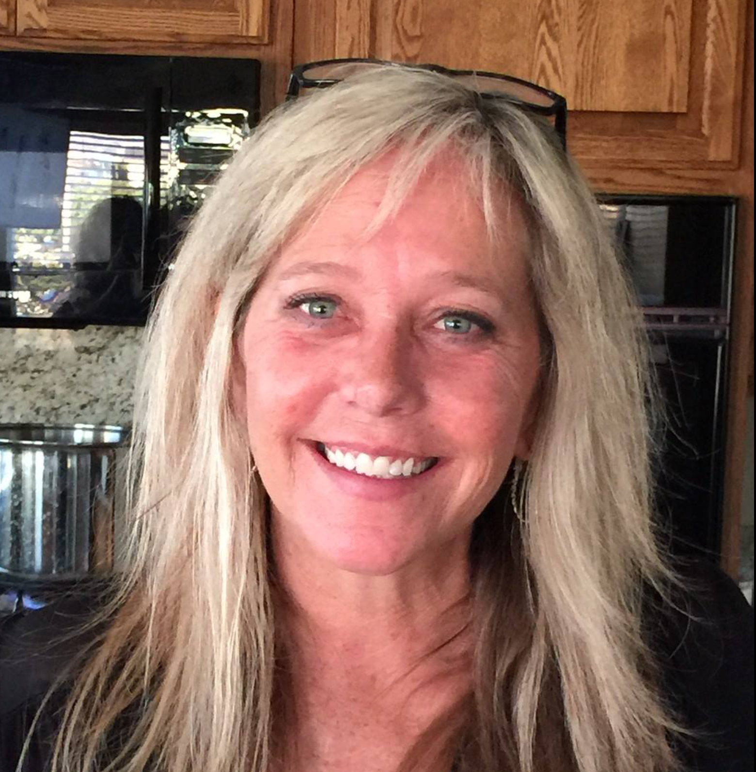 A woman with blonde hair and green eyes is smiling for the camera