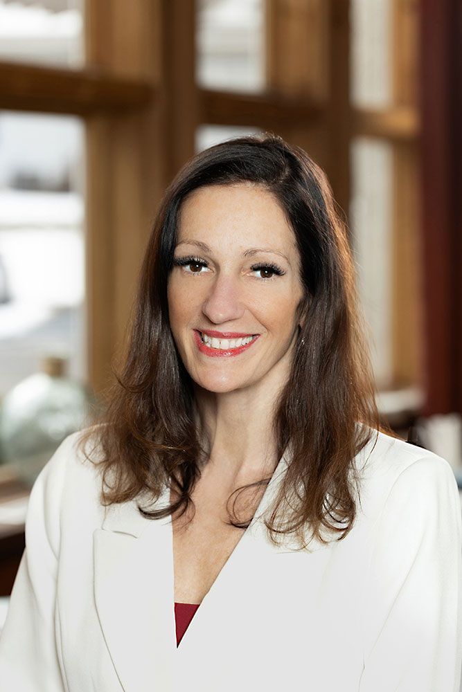 A woman in a white jacket is smiling for the camera.