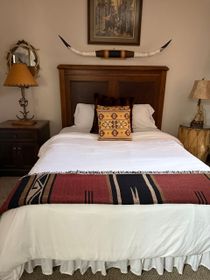 A bedroom with a queen bed and a painting on the wall