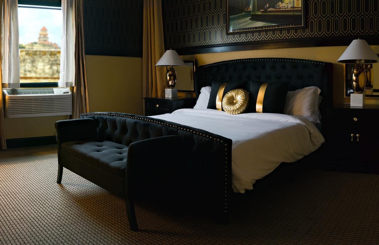A hotel room with a king size bed and a black couch