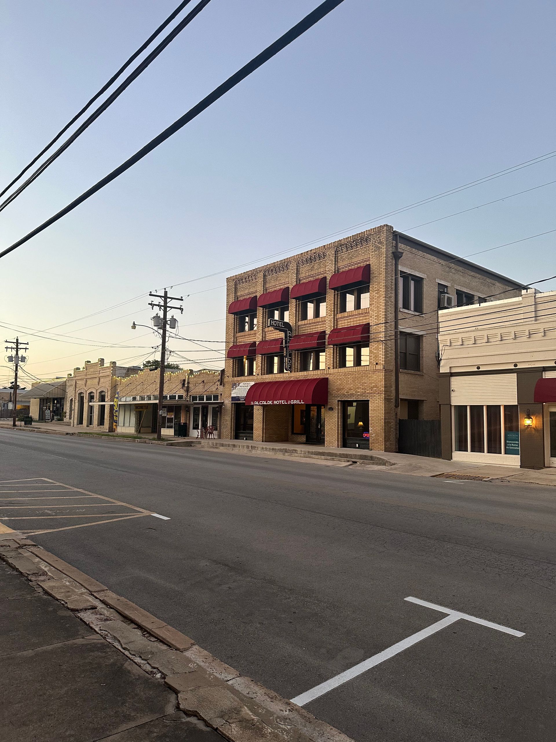 A brick building with red awnings is on the side of a street.
