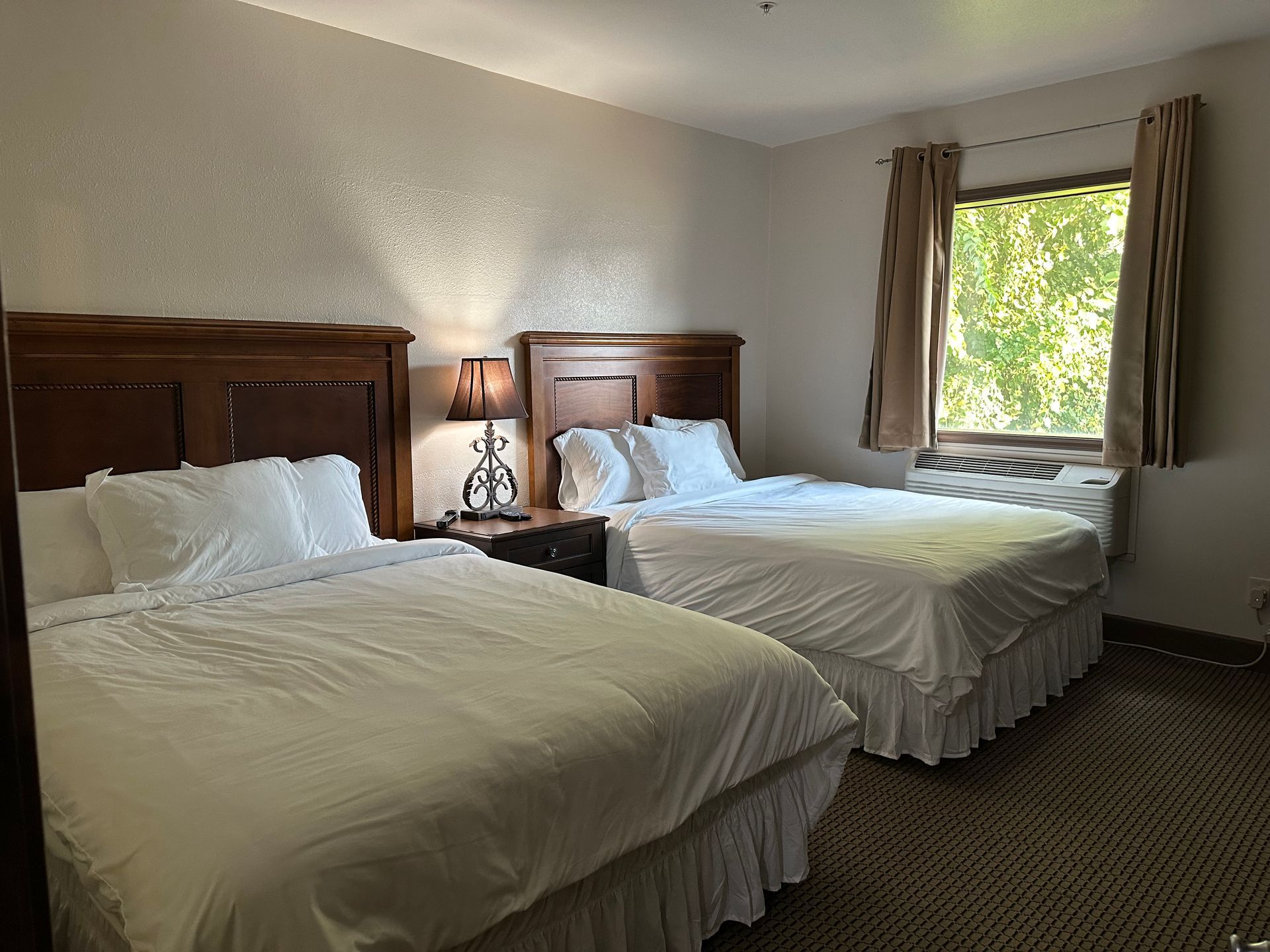 A hotel room with two beds and a window.