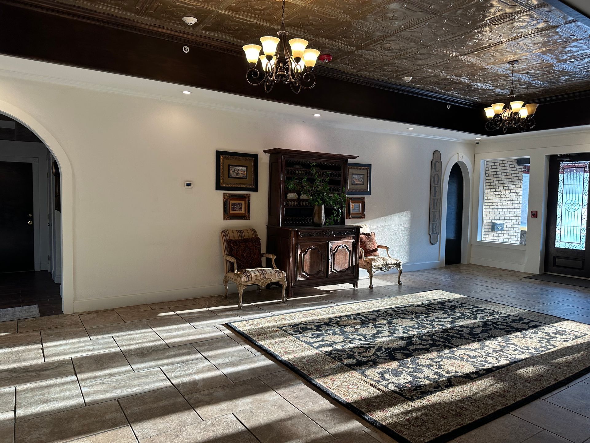 A large room with a rug , chairs , and a chandelier.