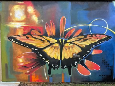 A painting of a butterfly on a flower on a wall.