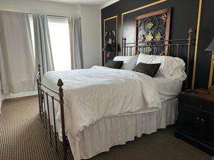 A bedroom with a King bed , nightstand , and window.