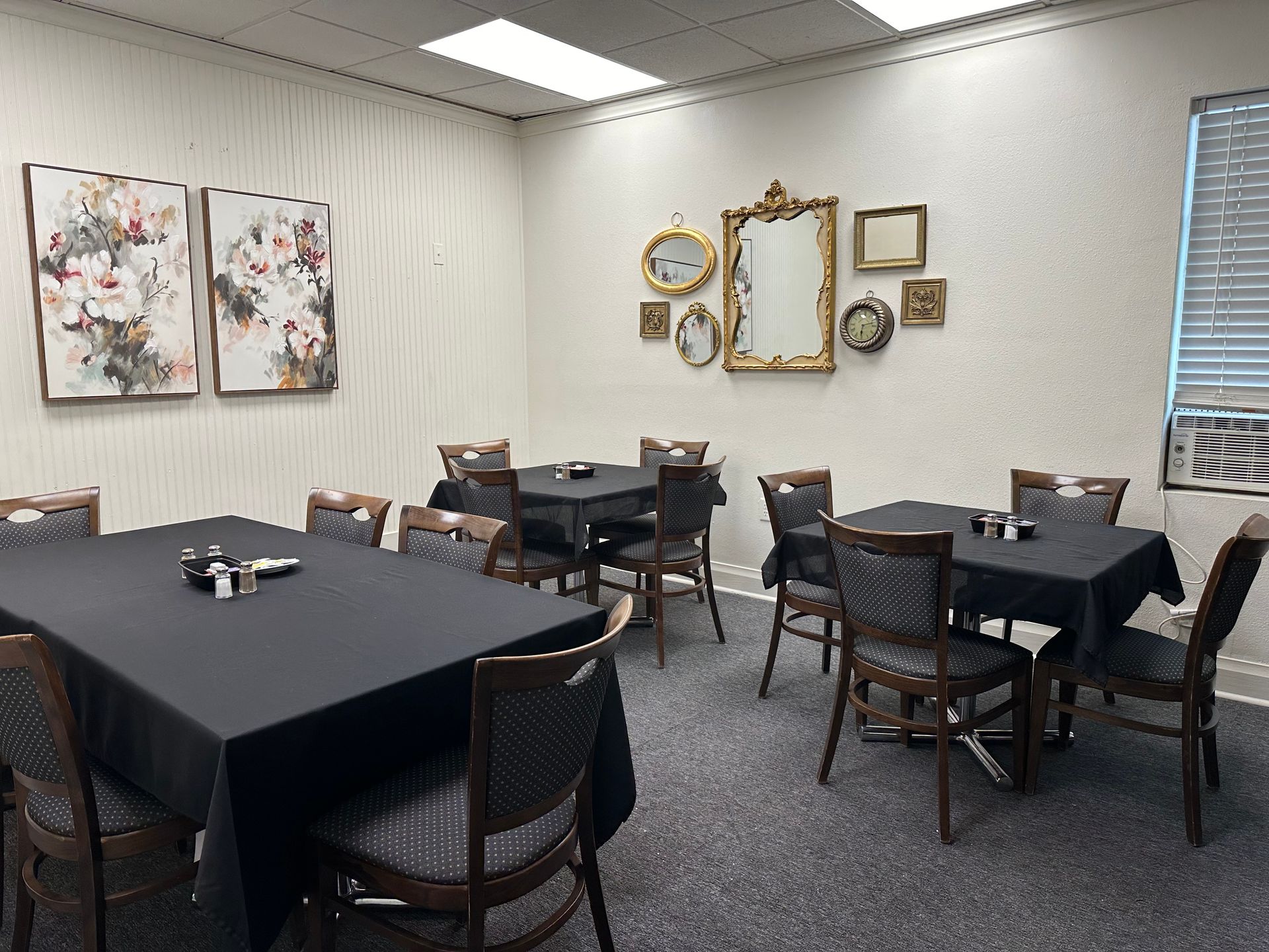 A room with tables and chairs and paintings on the wall.