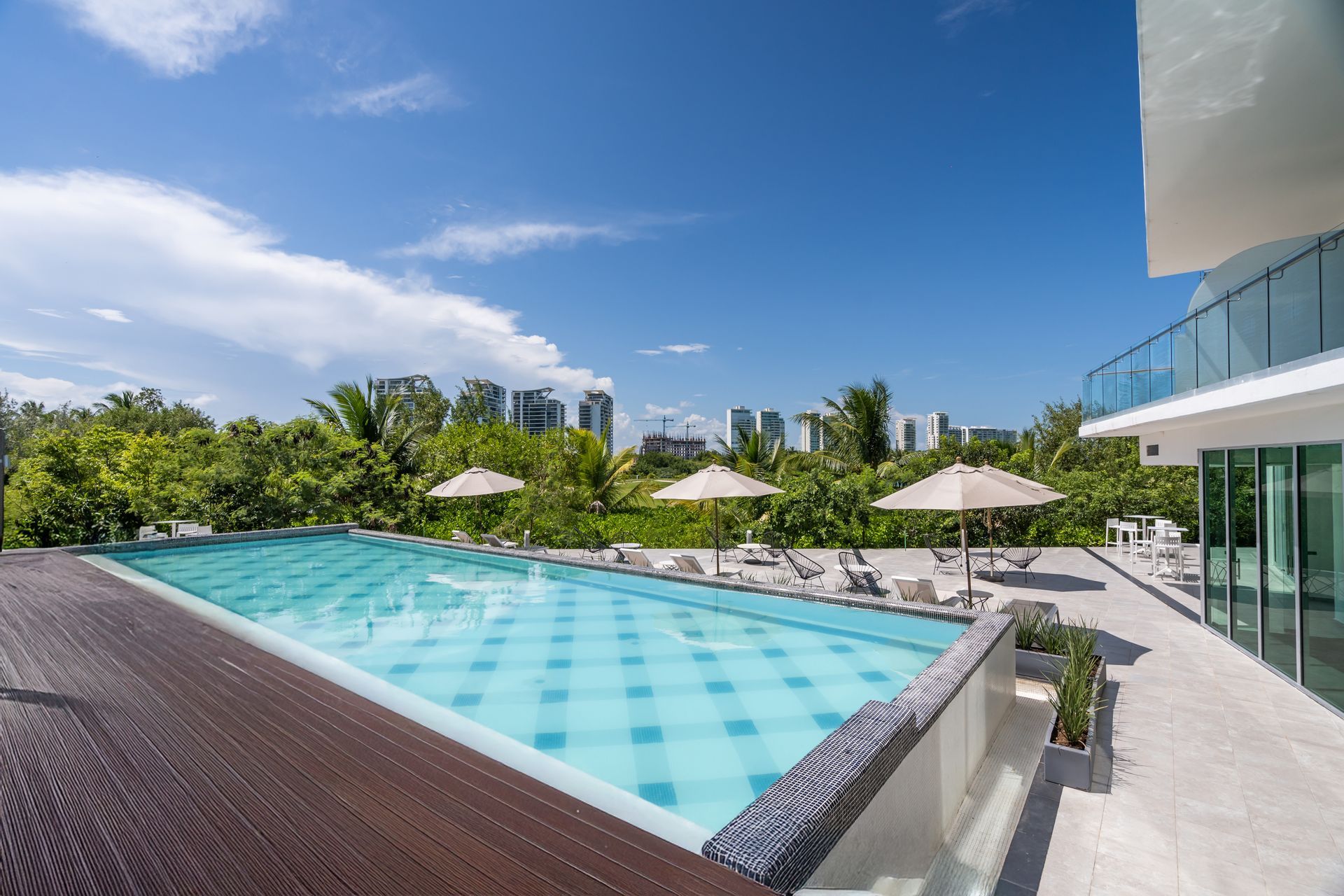 Una gran piscina con sombrillas y sillas frente a un edificio.