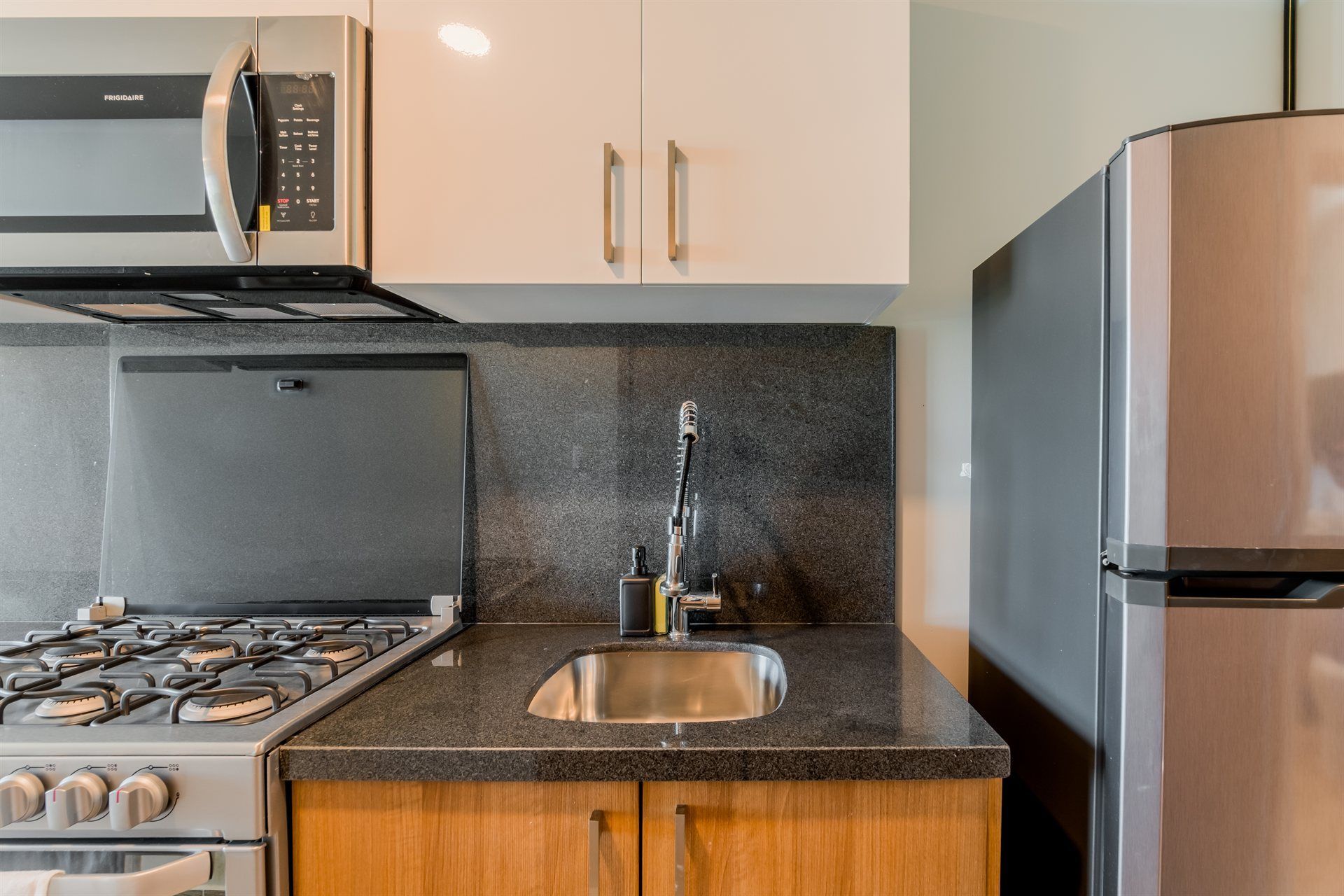 Una cocina con estufa, fregadero, microondas y refrigerador