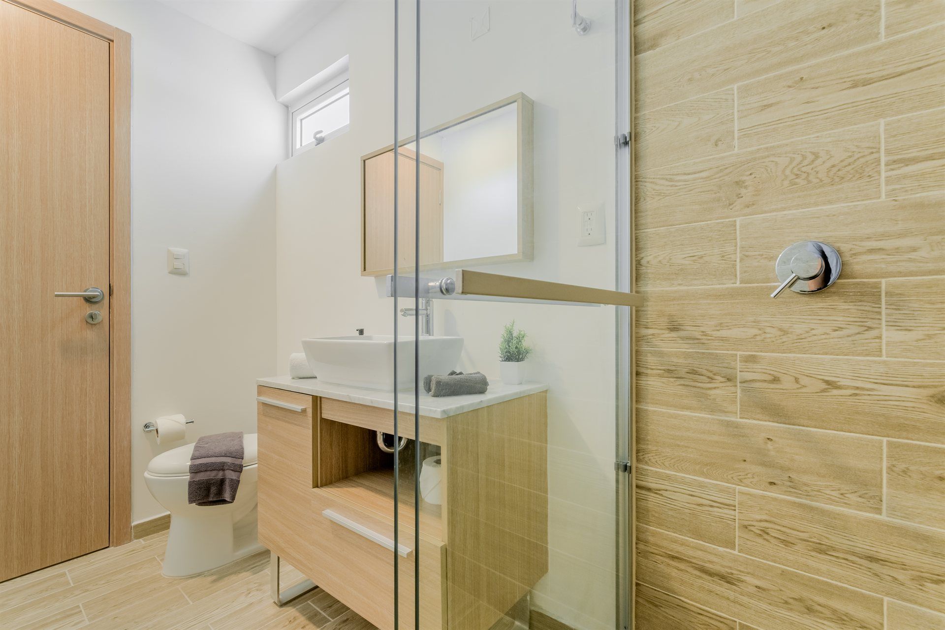 Un baño con inodoro, lavabo, espejo y ducha.