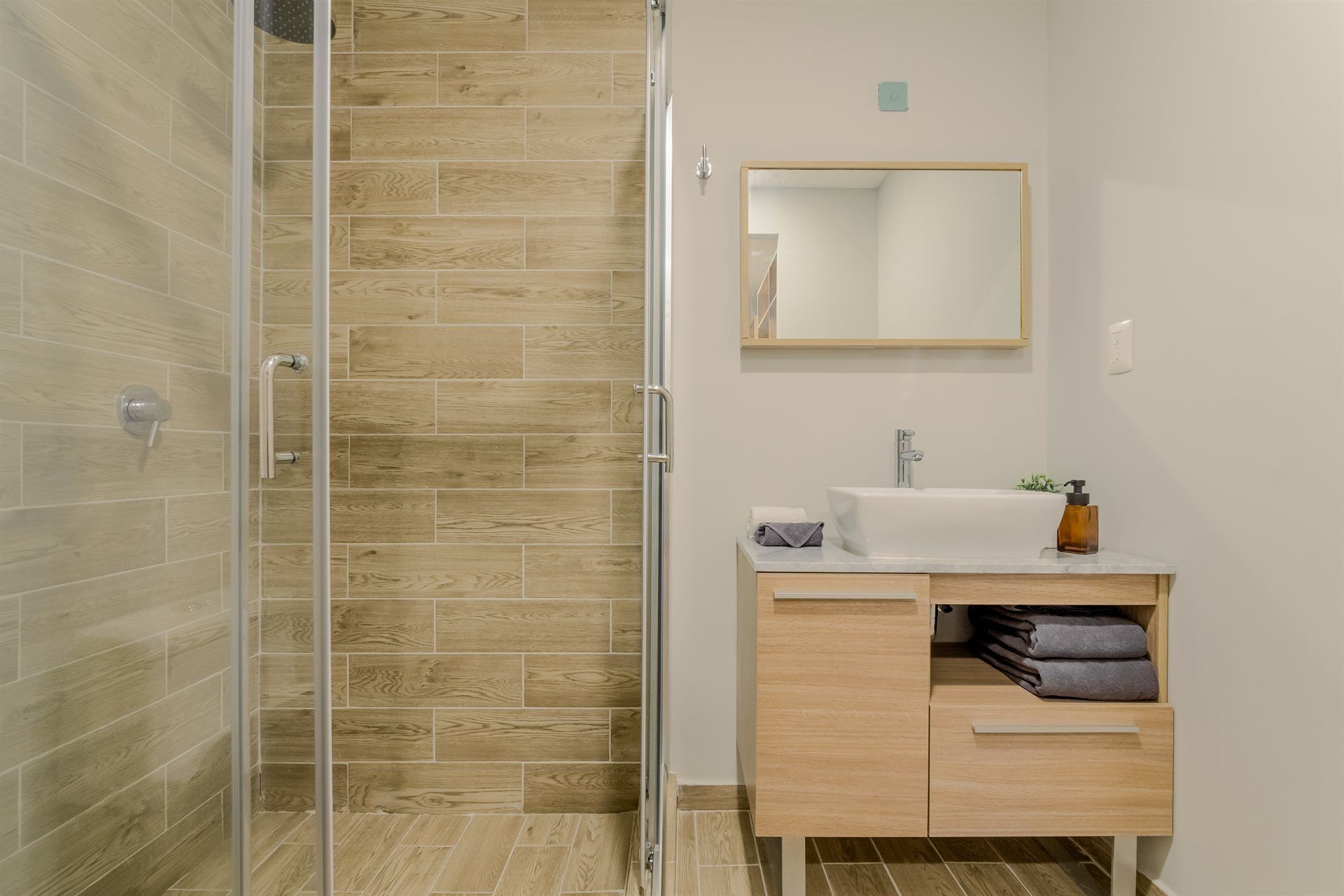 Un baño con lavabo, espejo y ducha.