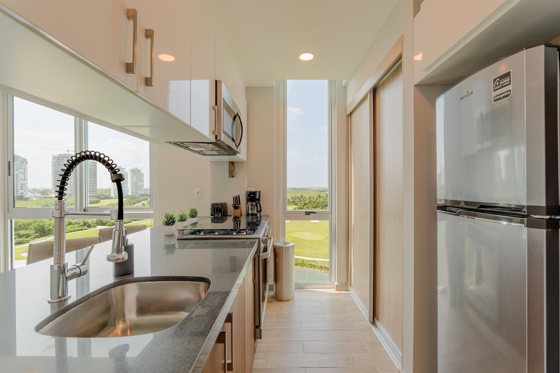 Una cocina con fregadero, refrigerador, microondas y puertas corredizas de vidrio.