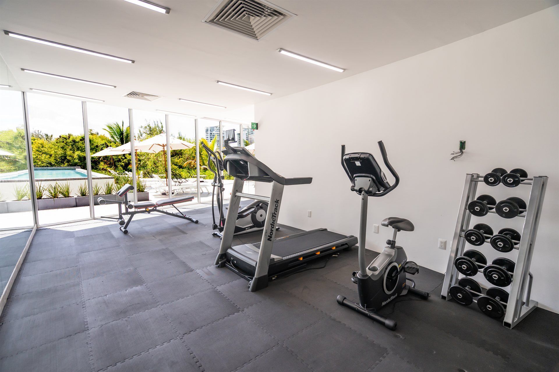 Un gimnasio con cintas de correr, una bicicleta y un soporte para mancuernas.