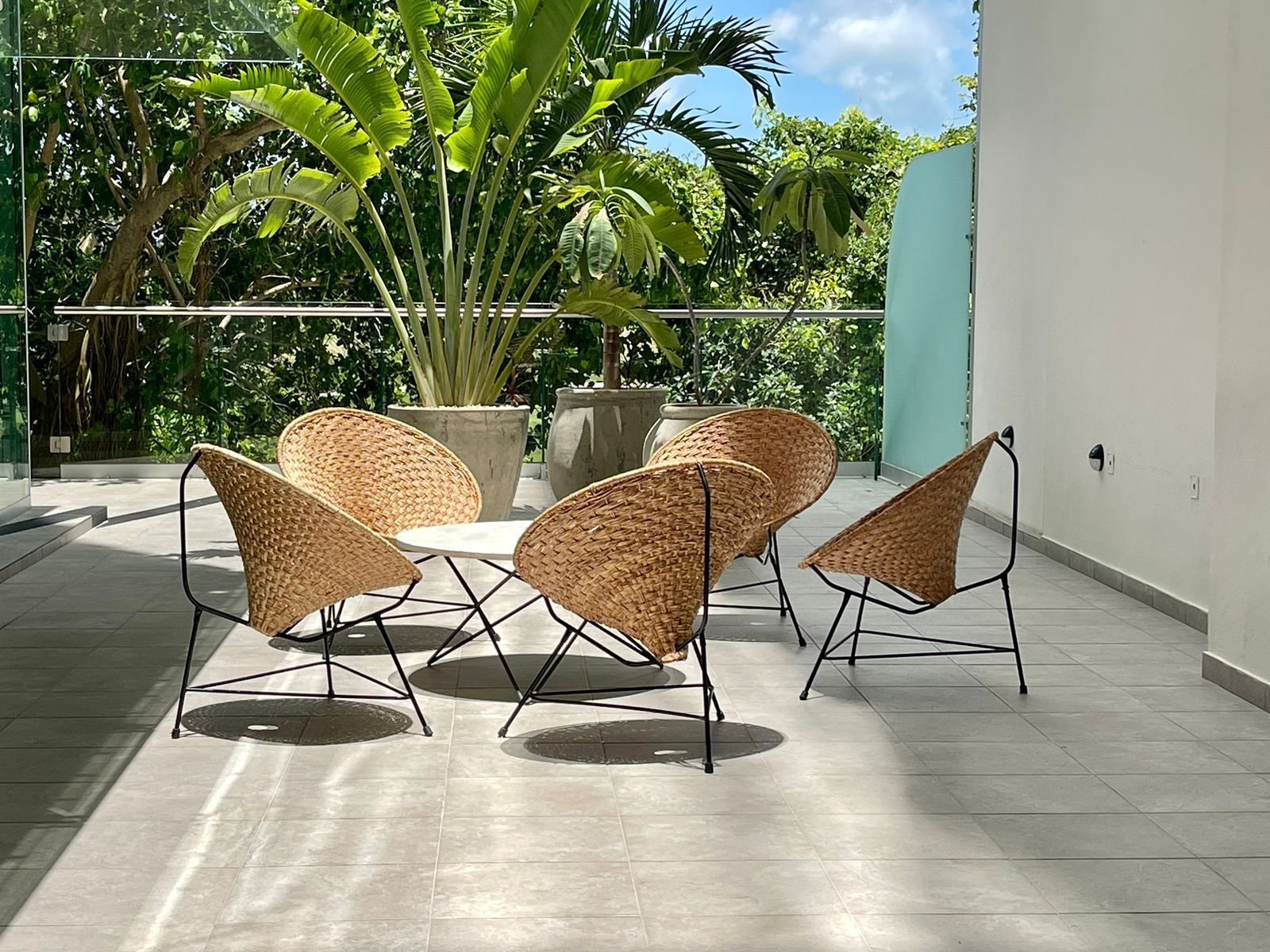 Un balcón con sillas de mimbre y una mesa.