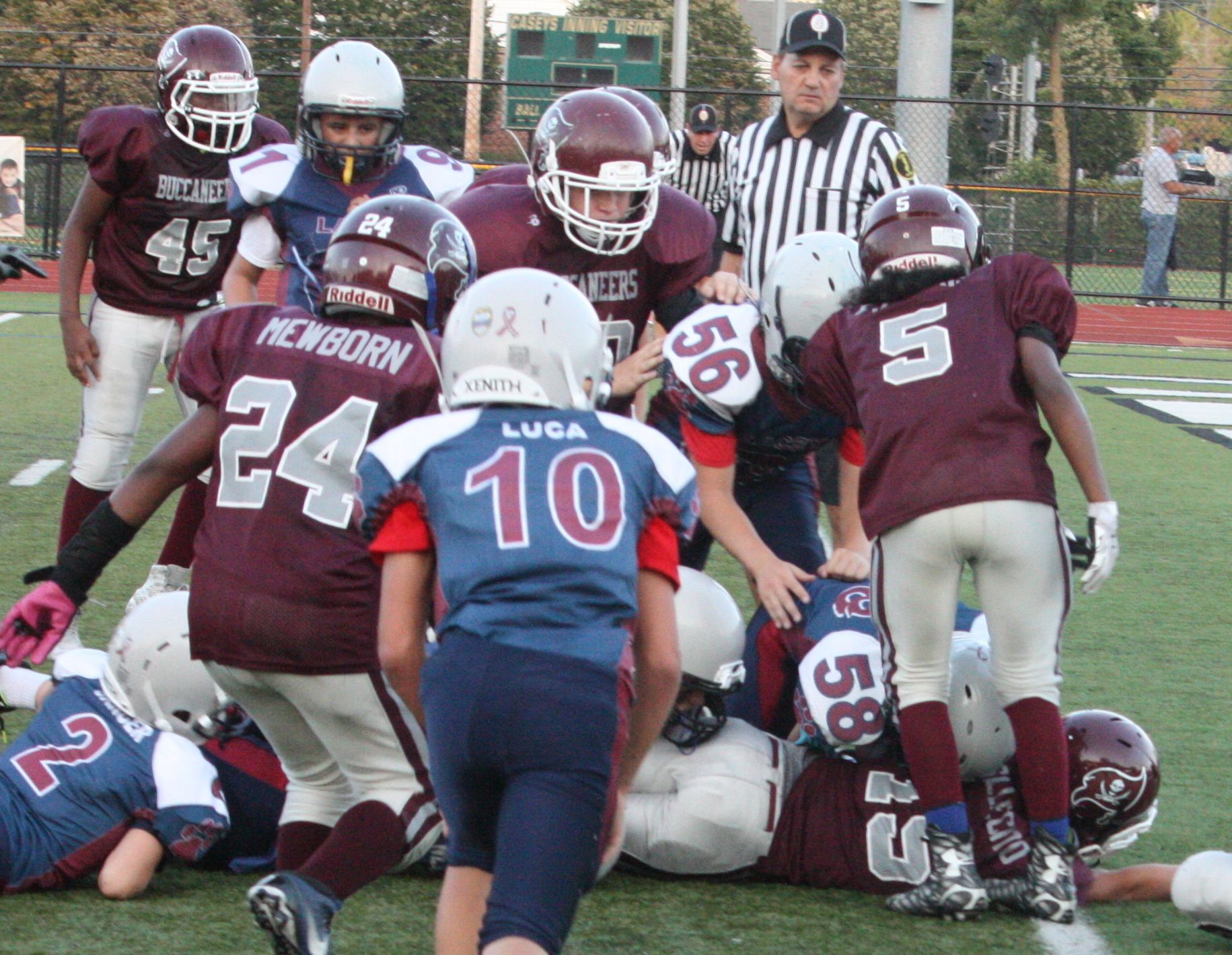 Football player holding a football on a green field at a stadium at night.