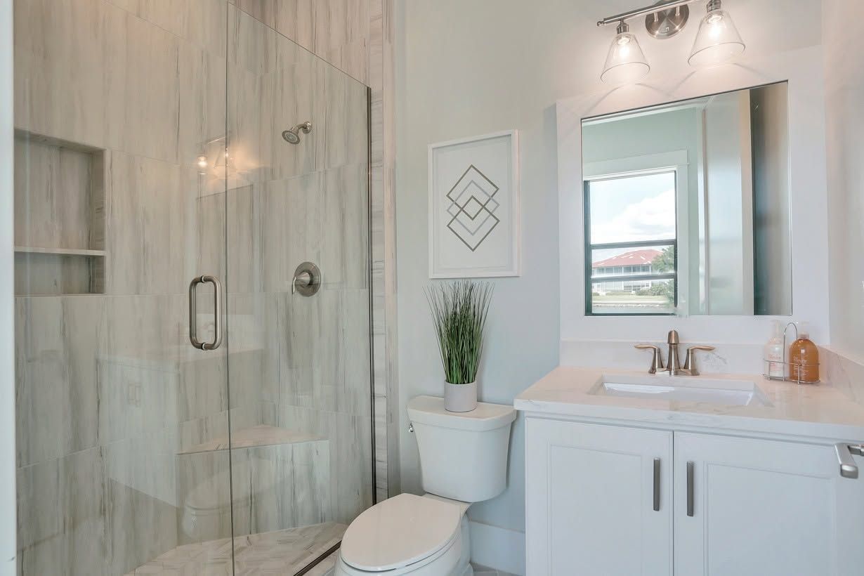Modern white bathroom with glass shower, vanity, mirror, toilet, and wall art