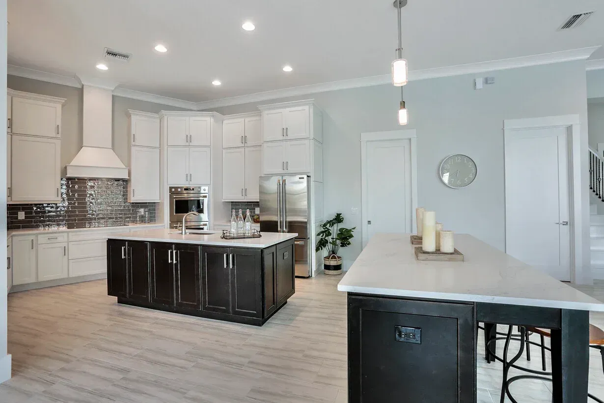 Bright modern kitchen with white cabinets, black island, and stainless steel appliances